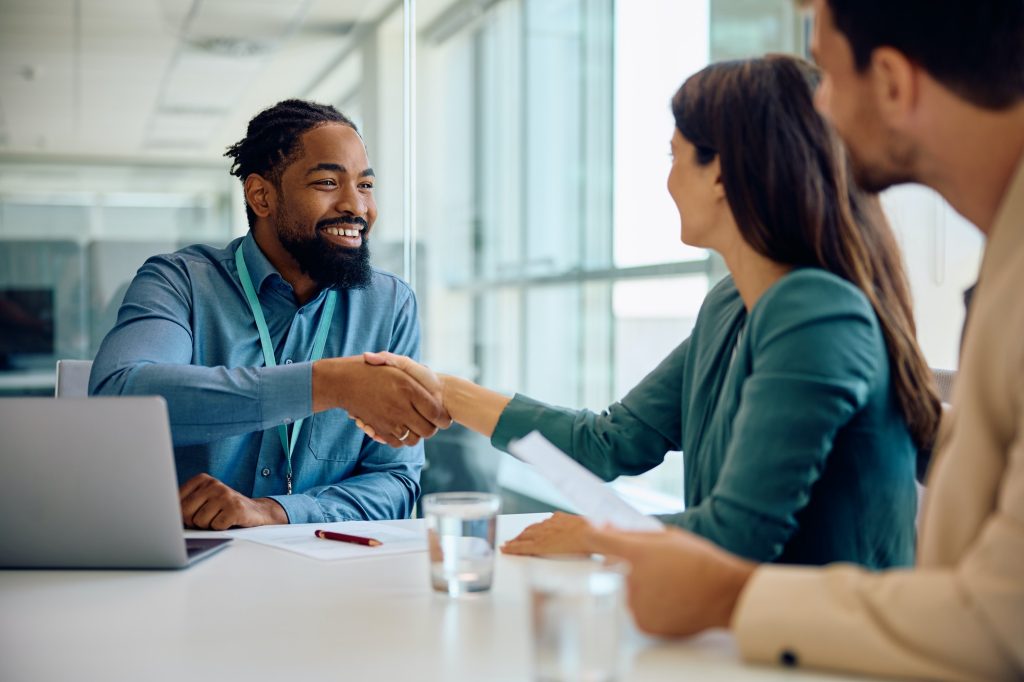 Happy black financial advisor handshaking with his clients during a meeting in the office.